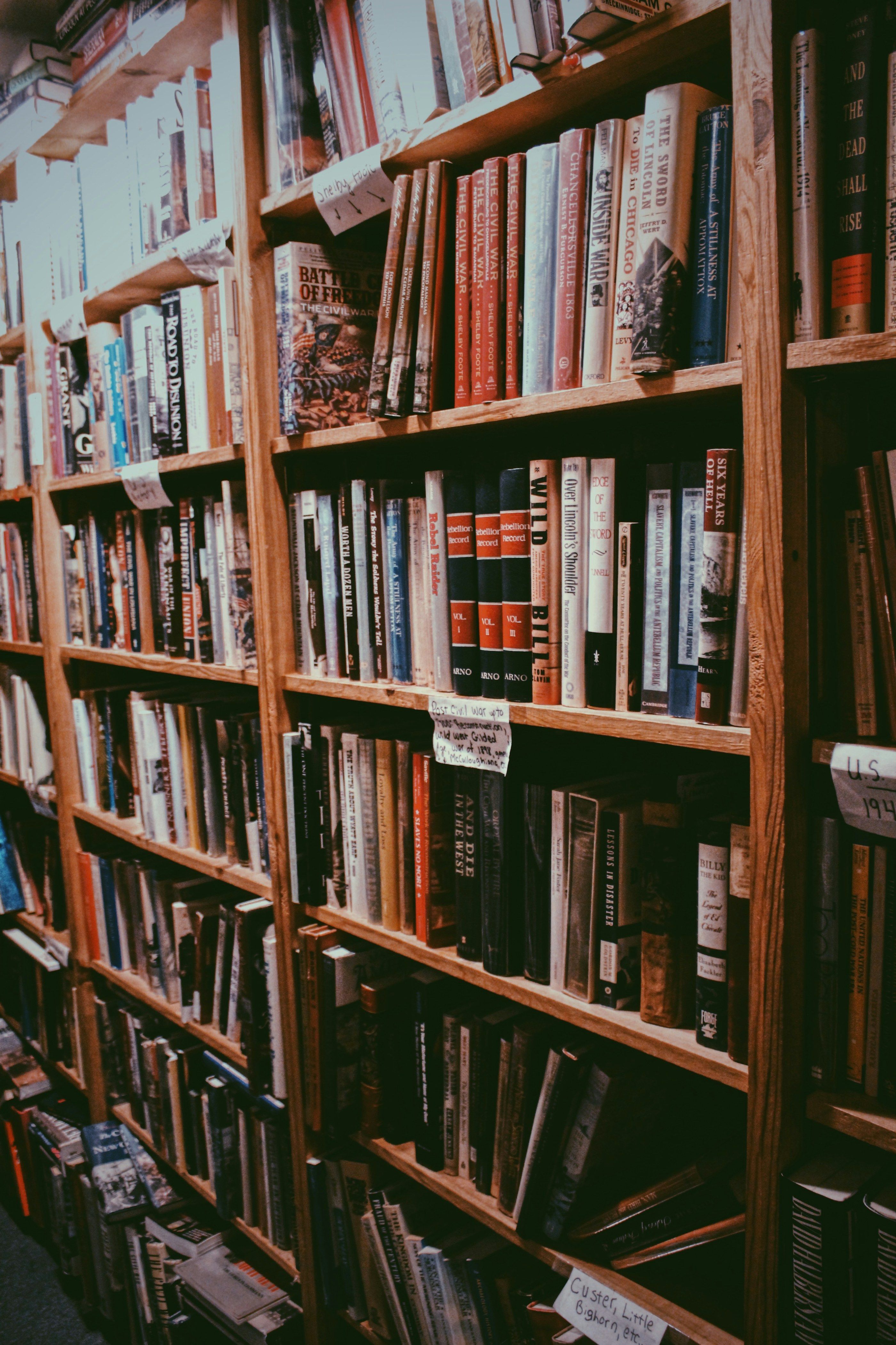 Tall wooden shelves full of books in a bookstore